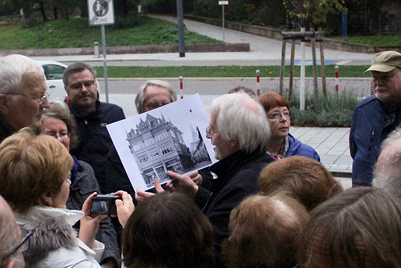 Führungsleiter zeigt altes Wohnhaus